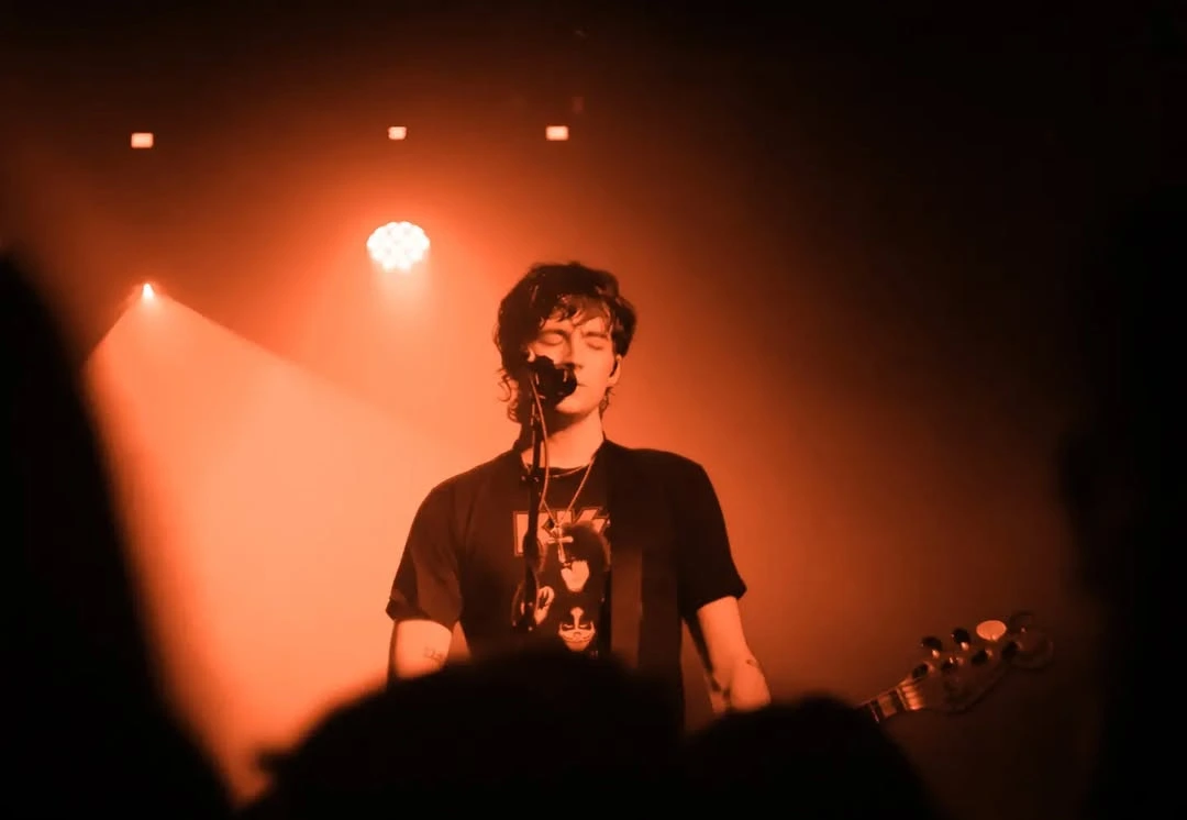 Elijah Hewson cantando bajo luces naranjas